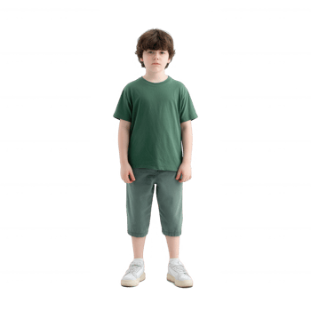 A young boy standing straight in a green t-shirt and light pants, looking directly at the camera with a neutral expression, isolated on a white background. png