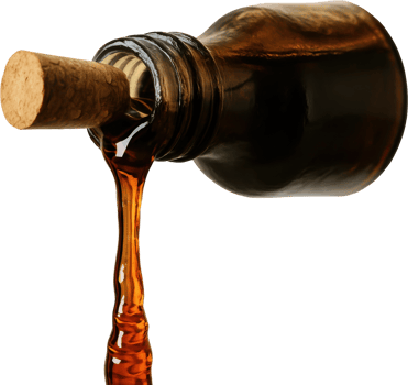 Dark amber maple syrup pouring from glass bottle with cork png