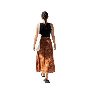 A woman in a patterned skirt walks away, her braid swaying gently as she carries a tote bag on a sunny day isolated on transparent background png
