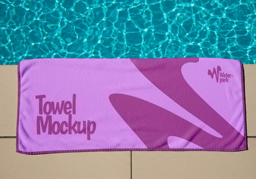 A purple towel mockup for a water park beside a swimming pool psd