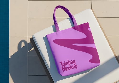 A purple tote bag with a trendy design rests on a lounge chair by the pool psd