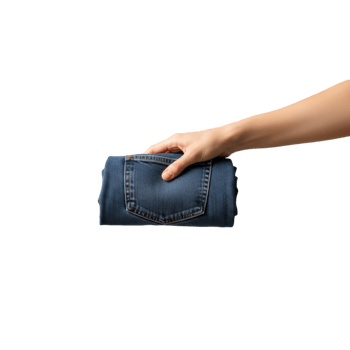 A persons hand is holding a neatly folded pair of blue denim jeans against a png
