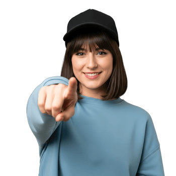 Young woman wearing a black baseball cap and blue sweatshirt pointing forward with a smile isolated on transparent background png