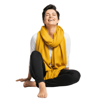 A happy woman with short hair laughs joyfully, sitting comfortably on the floor in a white shirt, black pants, and a bright yellow scarf. Ideal for themes of happiness, relaxation, and well being. png