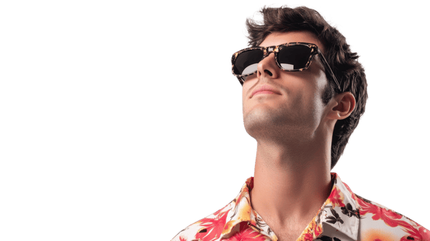 A young man stands confidently in a vibrant floral shirt and sunglasses, gazing upward in bright studio light png