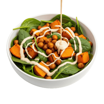 A healthy and delicious plant based salad featuring fresh spinach, roasted pumpkin, and crispy chickpeas, with a creamy dressing being poured over it. Perfect for a nutritious meal. png