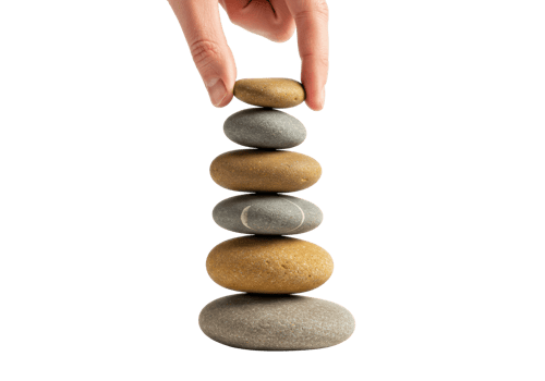 Balanced stack of river stones with hand on top creating harmony and balance. png